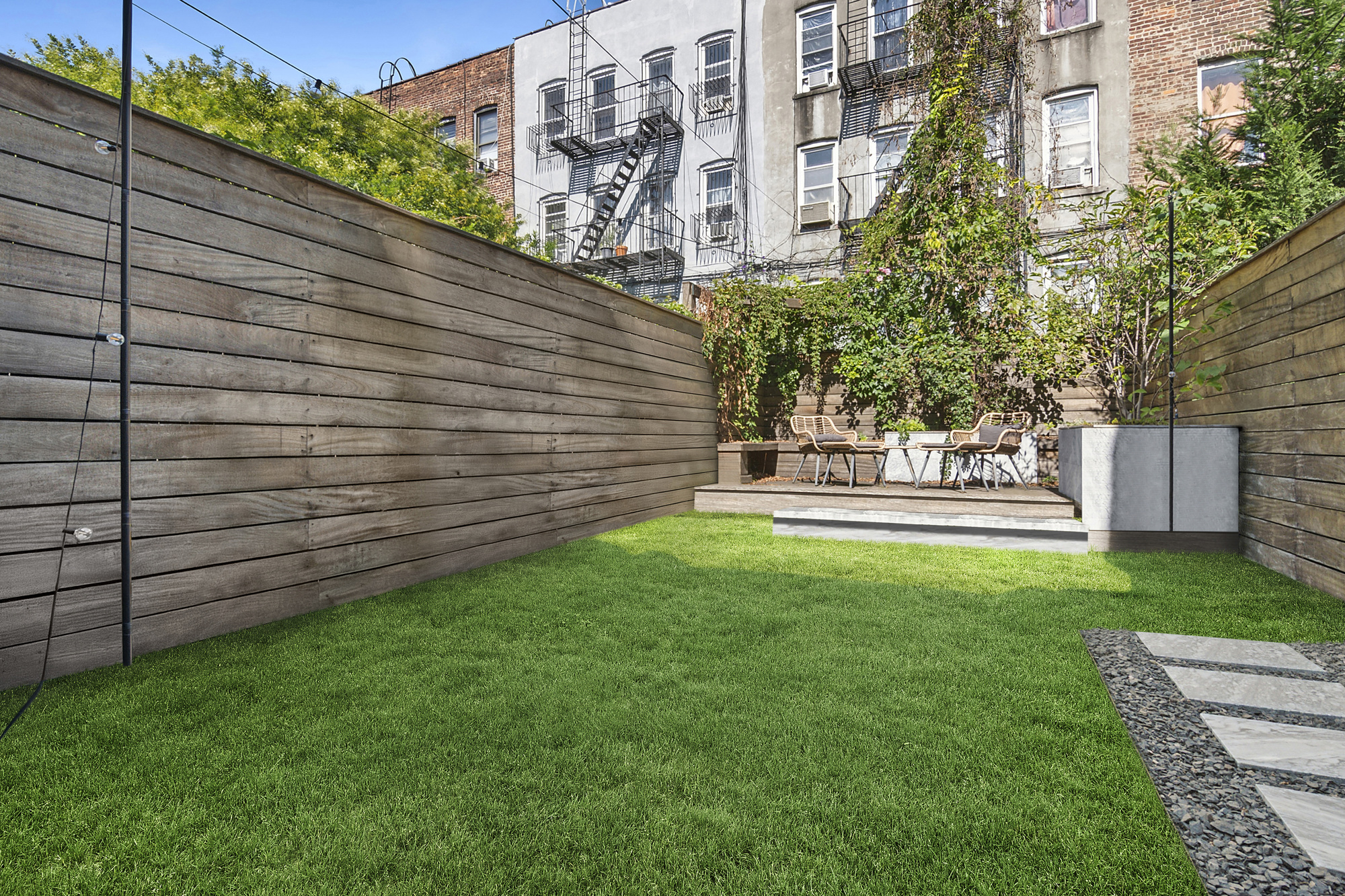 Landscaped backyard with lawn, cedar fence, and rear deck