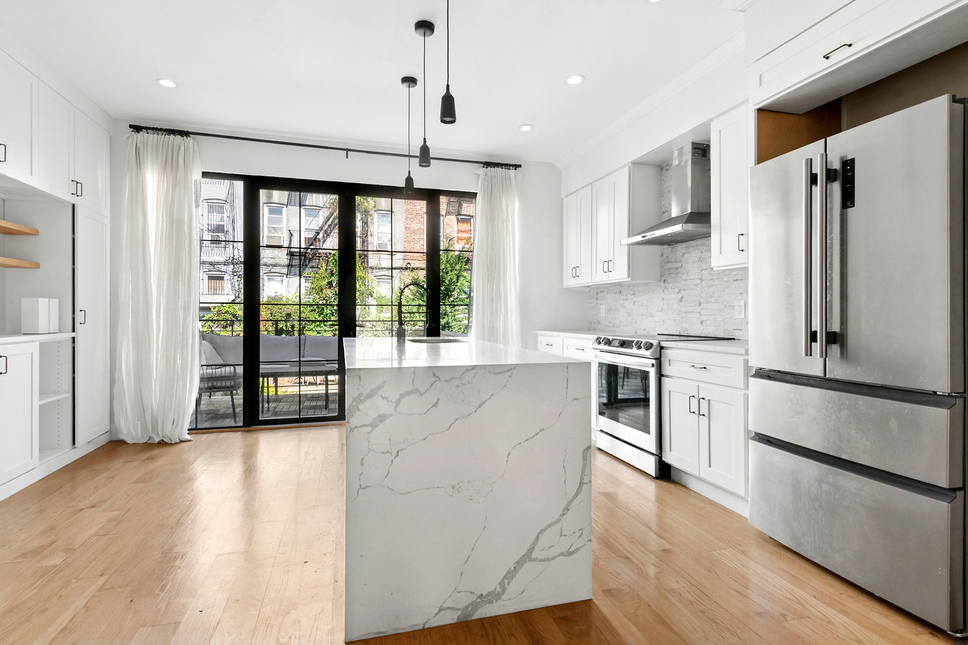 Renovated kitchen with marble waterfall island and stainless appliances