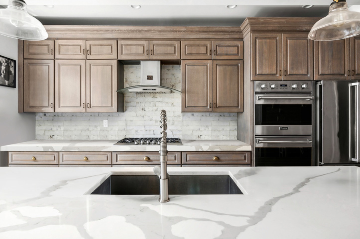 Renovated kitchen at 301 Cooper with marble waterfall island and wood cabinetry
